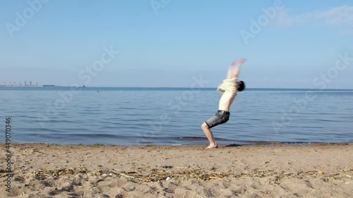 gymnast doing a back handspring on the beach in the water. a series of back handsprings or elements of acrobatics. several somersaults in a row against the background of the sea on the sand. photo