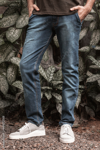 Męskie spodnie jeans niebieskie na modelu na naturalnym tle, zdjęcie reklamowe na baner.