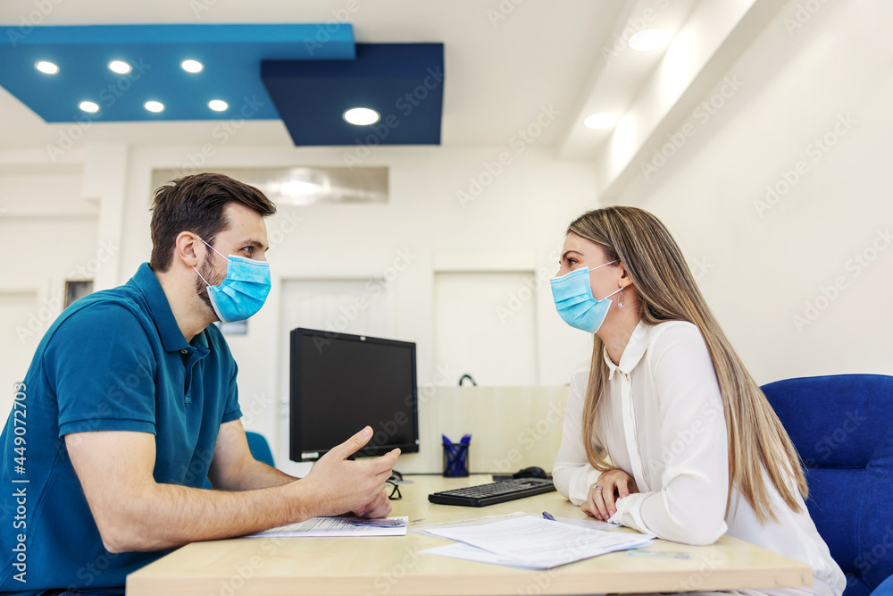 Obraz premium Paperwork for technical inspection and corona virus. A man and a woman are in a meeting in the office. The man explains something with his hands as she looks him straight in the eye