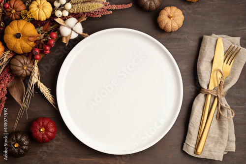 Rustic menu mockup with plate and autumn table decoration.  Floral interior decor for fall holidays with handmade pumpkins. Holiday dinner concept. Flatlay, top view.