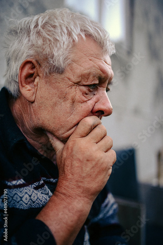 an elderly man looks thoughtfully into the distance