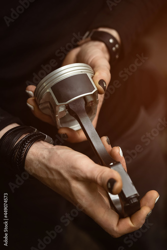 Engine piston in the hands with manicure. Manual worker's identity and diversity.
