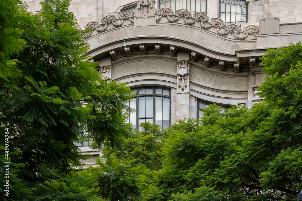 Fachada de bellas artes en la Ciudad de México con ventanales y arboles al frente.