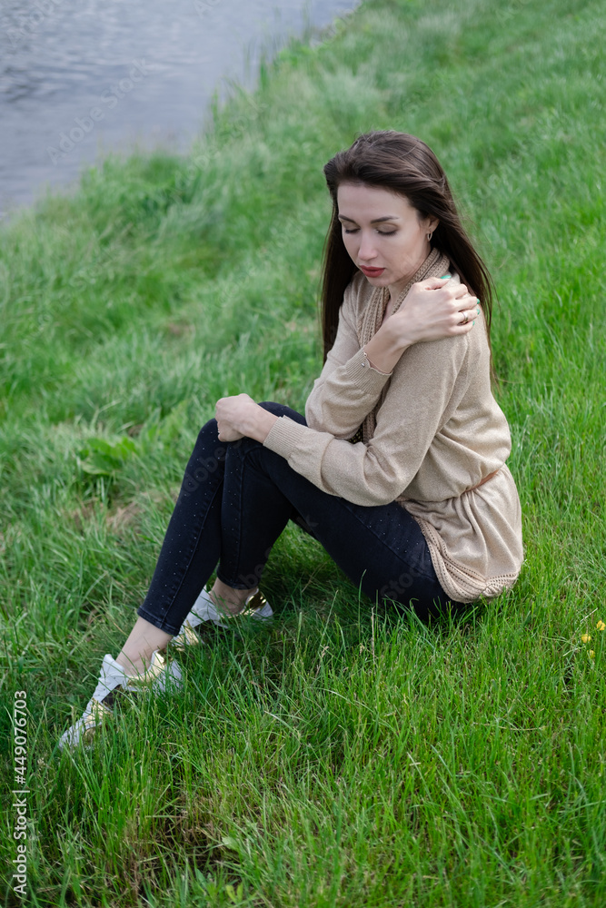 beautiful brunette woman sitting on green grass. beautiful brunette woman sitting on green grass.