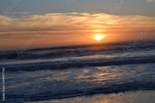 orange sun setting on the west coast horizon with a view of the ocean tide © Kerrin