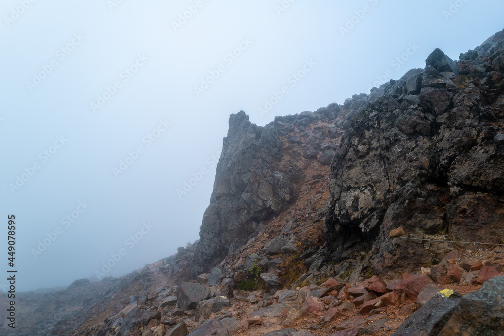 Naklejka premium 栃木県那須郡那須町の那須岳に霧の中で紅葉を見るために登山している風景 A view of climbing Mt. Nasu in Nasu-machi, Nasu-gun, Tochigi Prefecture, to see the autumn leaves in the fog.