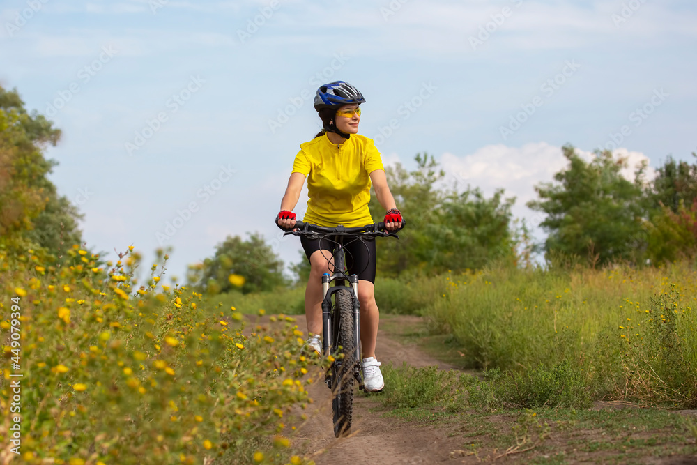 beautiful and happy woman cyclist rides a bicycle on the road in nature. Healthy lifestyle and sports. Leisure and hobbies