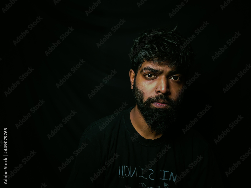 Fototapeta premium Indian bearded man with facial hair and expressions for social media posts and web banners with black background wearing a black tshirt studio shot of indian male model with piercing