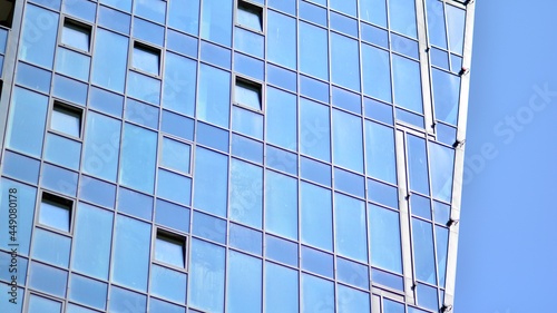 Futuristic facade of a modern office building clad in glass. Glass cladding panels and windows of modern building. An office building with geometry and perspective.