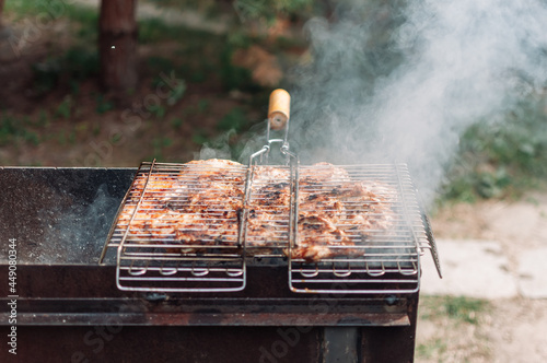 Cooking marinated chicken thighs in sauce and spices on griddle on grill.Juicy cuts of meat marinated with smoke rising from charcoal. Fried chicken kebab over an open fire. Campfire cooking season.