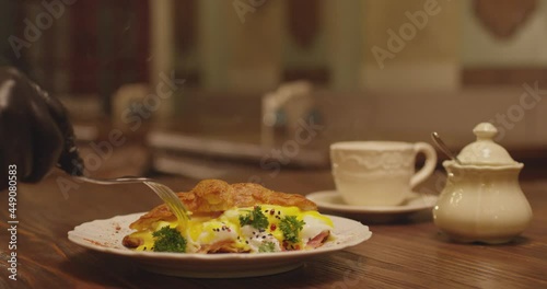 Slow motion of pouring egg juice from croissant into plate . Professional chef slicing croissant omelette by fork . Breakfast items on table inside restaurant . Shot on RED EPIC Camera . photo