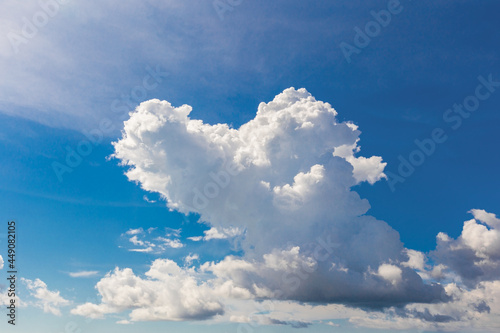 Heart shaped cloud on bright blue sky.