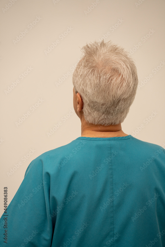 Rear view of a medical doctor or nurse glancing at a white wall Rear view of a medical doctor or nurse glancing at a white wall