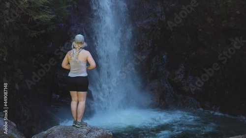 Adult Woman hiker at Norvan Falls and river stream in the natural canyon during the summer time. Canadian Nature Background. Lynn Valley, North Vancouver, British Columbia, Canada. Slow Motion photo
