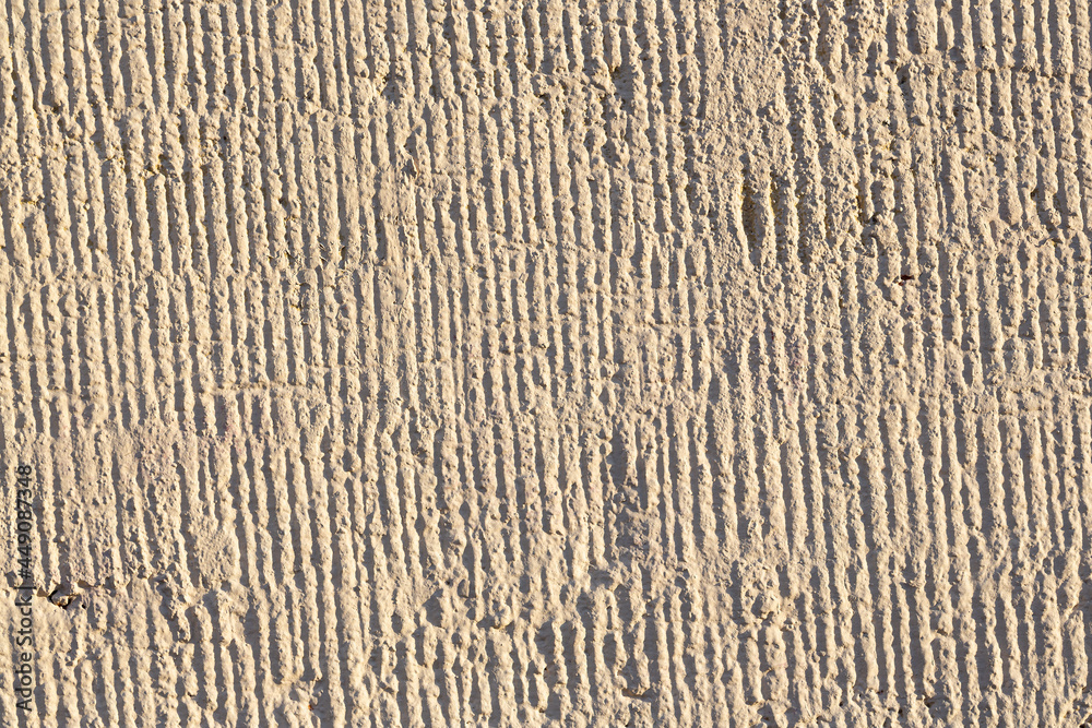 Texture of the wall. Decorative plaster. Rough painted surface with a pattern of vertical stripes, recesses and dents. Great for background and design. Close-up. Texture of the wall. Decorative plaster. Rough painted surface with a pattern of vertical stripes, recesses and dents. Great for background and design. Close-up.