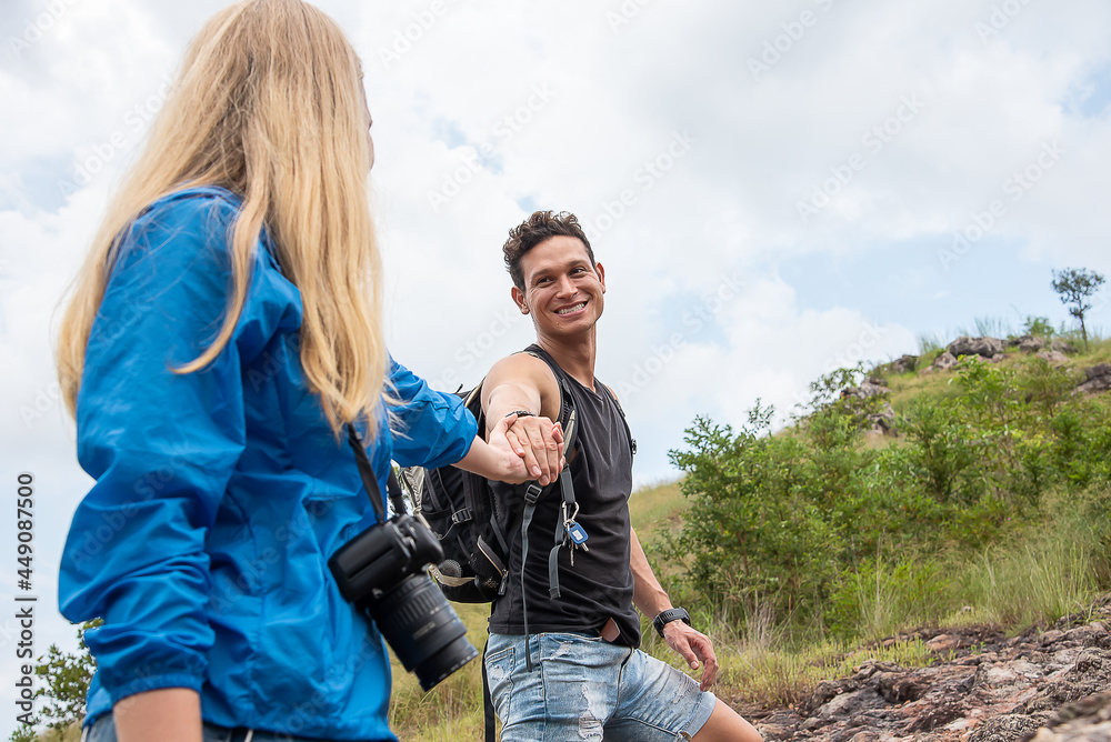 Handsome man carrying a hand bag to hold his girlfriend carrying a camera during a trekking trip