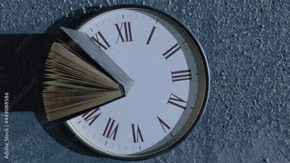 Book's pages turning by wind on 24 hours antique clock with classic roman numerals . Wind browse pages of old historic book . Mystical , abstract and symbolically video. Shot on ARRI Alexa camera .