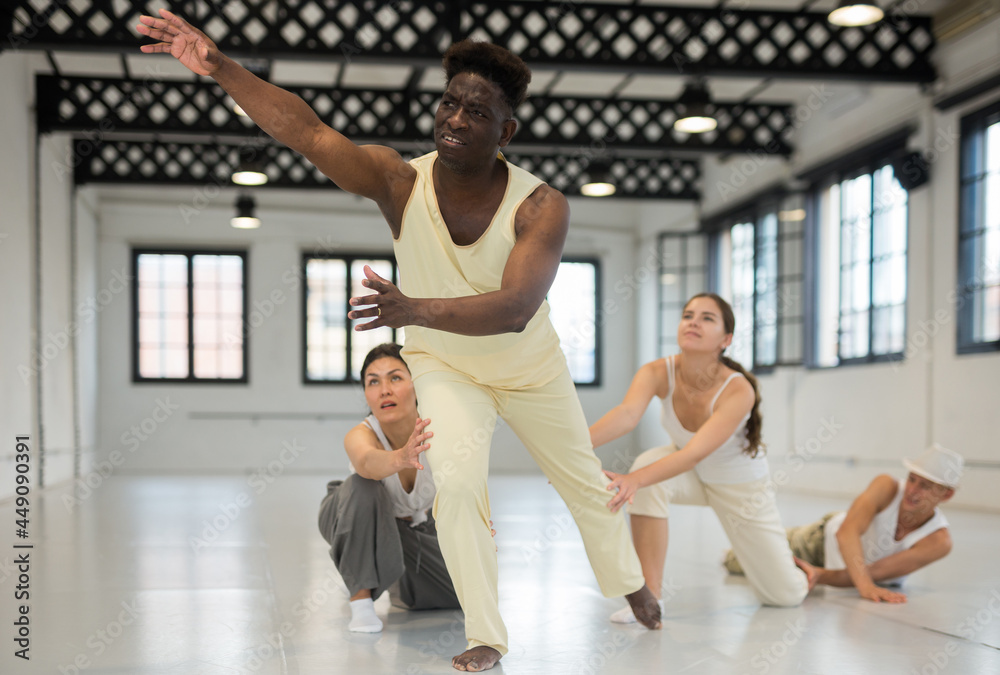 Obraz premium Positive afro american man studying movement of contemporary dance in classroom with his friends