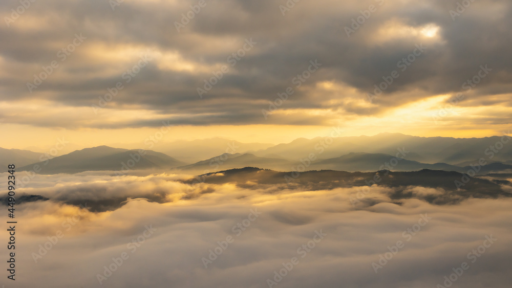 Sun rays through the clouds and beautiful mist in the mountains in wonderful morning sunrise natural landscape.