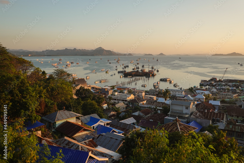 Sunset over the Labuan Bajo town and harbor, with many Phinisi traditional cruise boat anchored as the city is the entry point to the Komodo national park in Flores, Indonesia