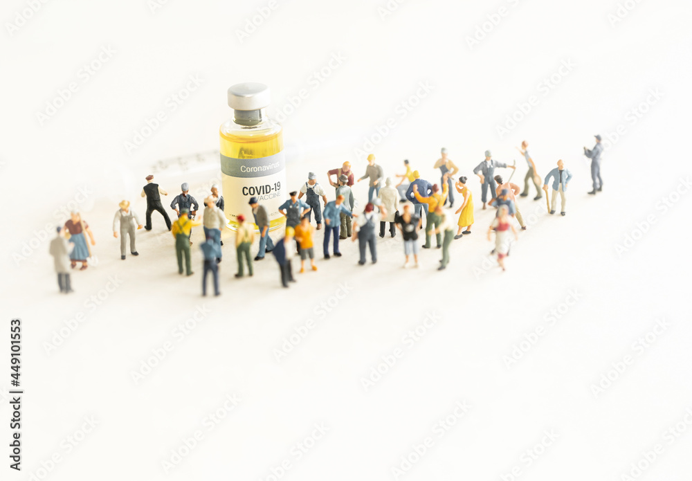 Group of people (figurine) standing against the Coronavirus COVID-19 vaccine and syringe for injection .Coronavirus vaccine, population immunization campaign concept background. Group of people (figurine) standing against the Coronavirus COVID-19 vaccine and syringe for injection .Coronavirus vaccine, population immunization campaign concept background.