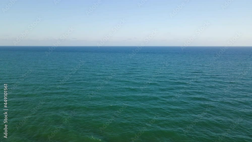 Aerial view of the horizon line of the Mediterranean sea on a clear day with waves coming in. Aerial view of the horizon line of the Mediterranean sea on a clear day with waves coming in.