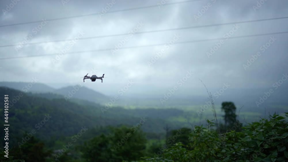 Small drone flying in slowmotion with foggy mountains in background Small drone flying in slowmotion with foggy mountains in background
