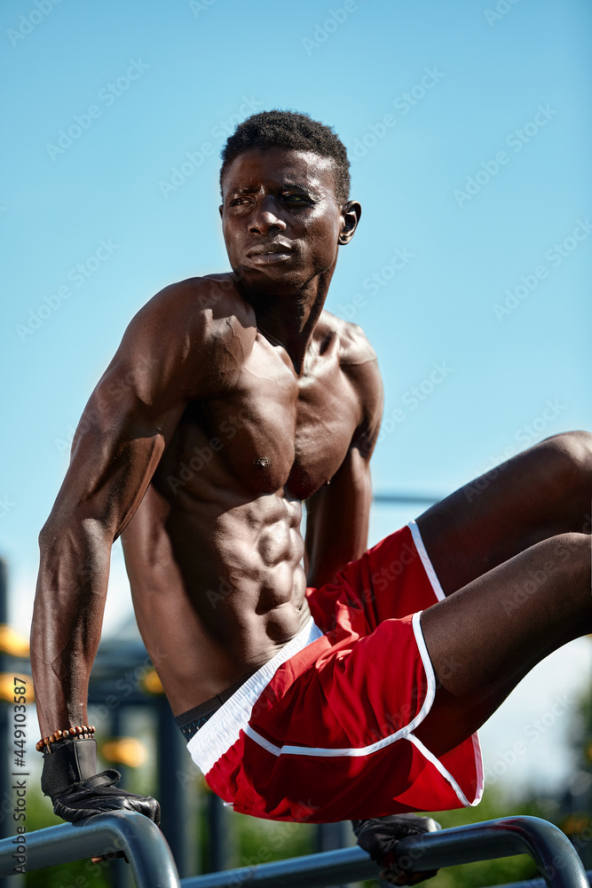 Black young man exercising on the uneven bars in the park, crossfit concept, african american man doing exercises on the uneven bars in the street, on the sports ground Black young man exercising on the uneven bars in the park, crossfit concept, african american man doing exercises on the uneven bars in the street, on the sports ground