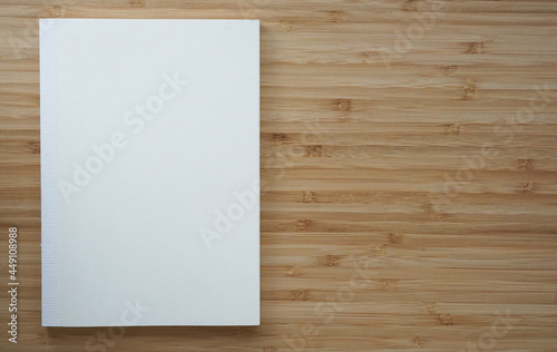木目調のテーブルに置かれた真っ白なノートブック