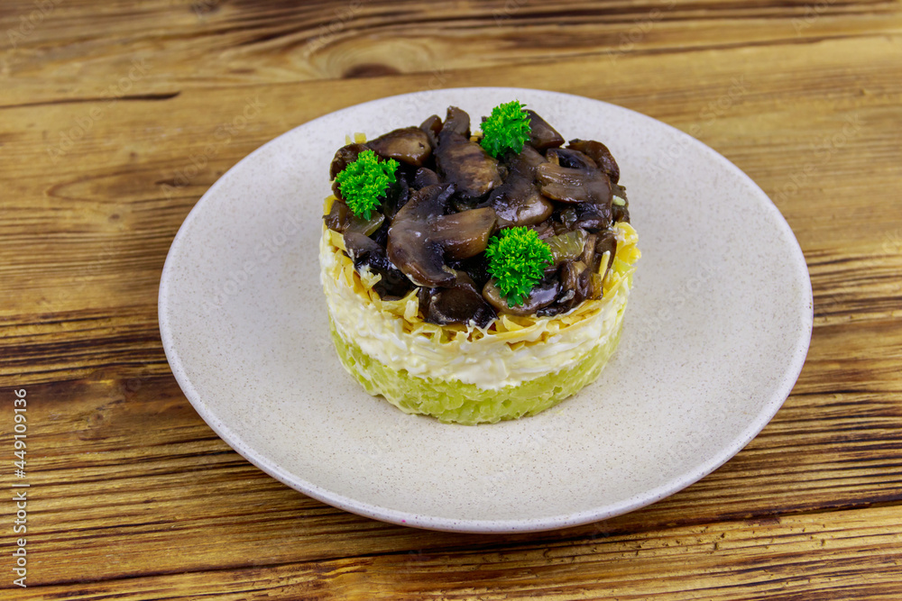 Tasty layered salad with roasted mushrooms, potato, eggs, cheese and mayonnaise on wooden table