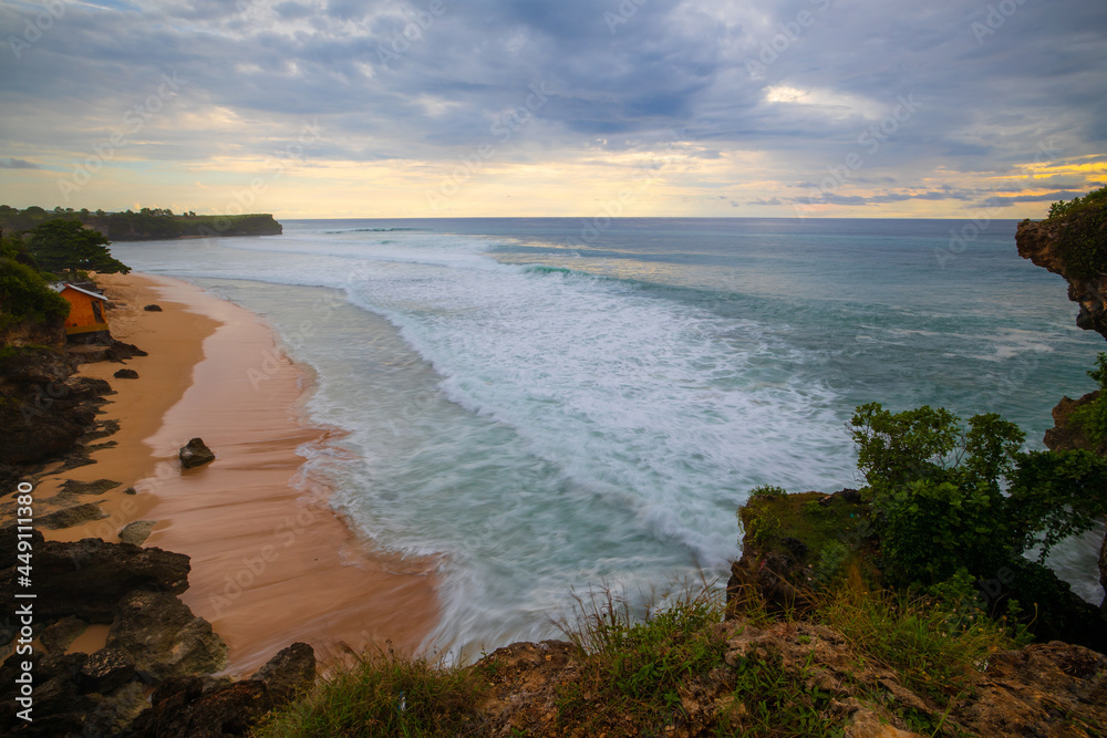 Fototapeta premium Seascape. Spectacular view from Balangan cliff in Bali. Sunset time. Blue hour. Ocean with motion foam waves. Waterscape for background. Nature concept. Soft focus. Slow shutter speed.