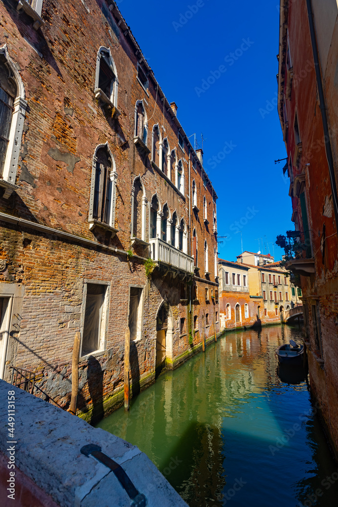 Scenic view of narrow Venetian canals with old colorful architecture in sunny day, Italy..
