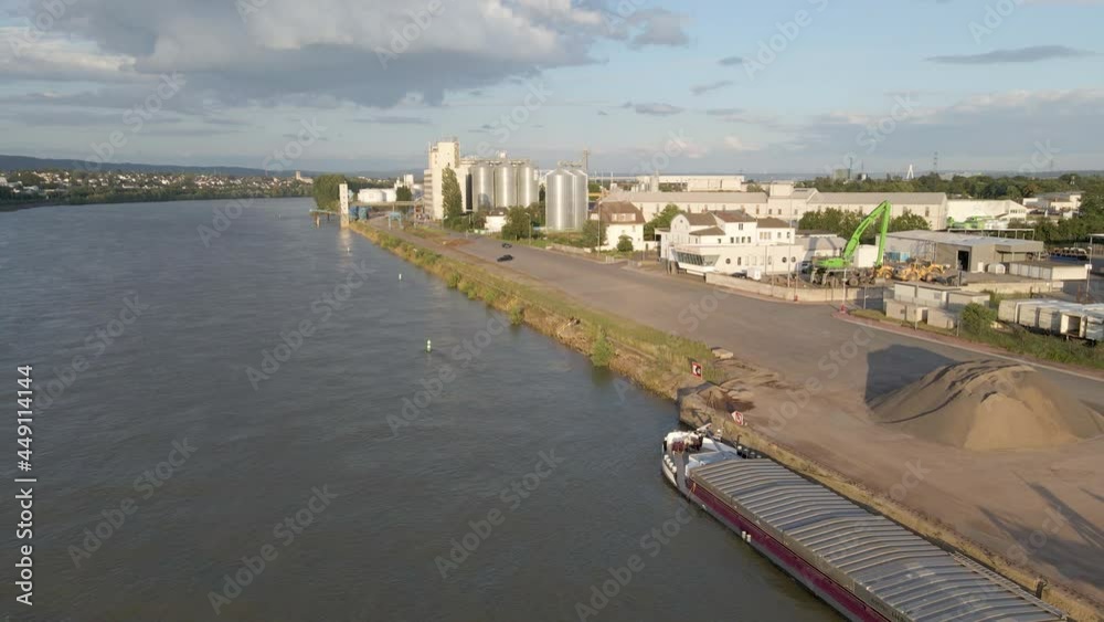 Flying towards large industrial silos on an industrial site near river