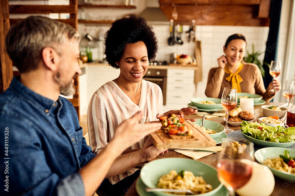 Smiling African American woman enjoys in lunch with her friends at home.