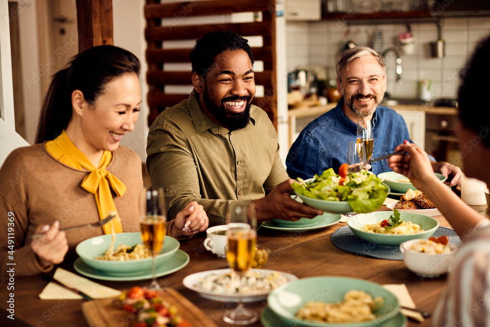Multi-ethnic group of happy friends enjoy while having lunch together at dining table. Multi-ethnic group of happy friends enjoy while having lunch together at dining table.