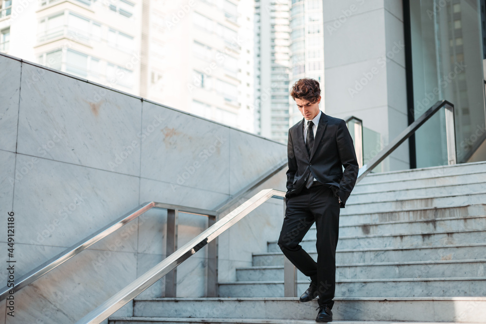young man in casual suit walking through a place with stairs young man in casual suit walking through a place with stairs