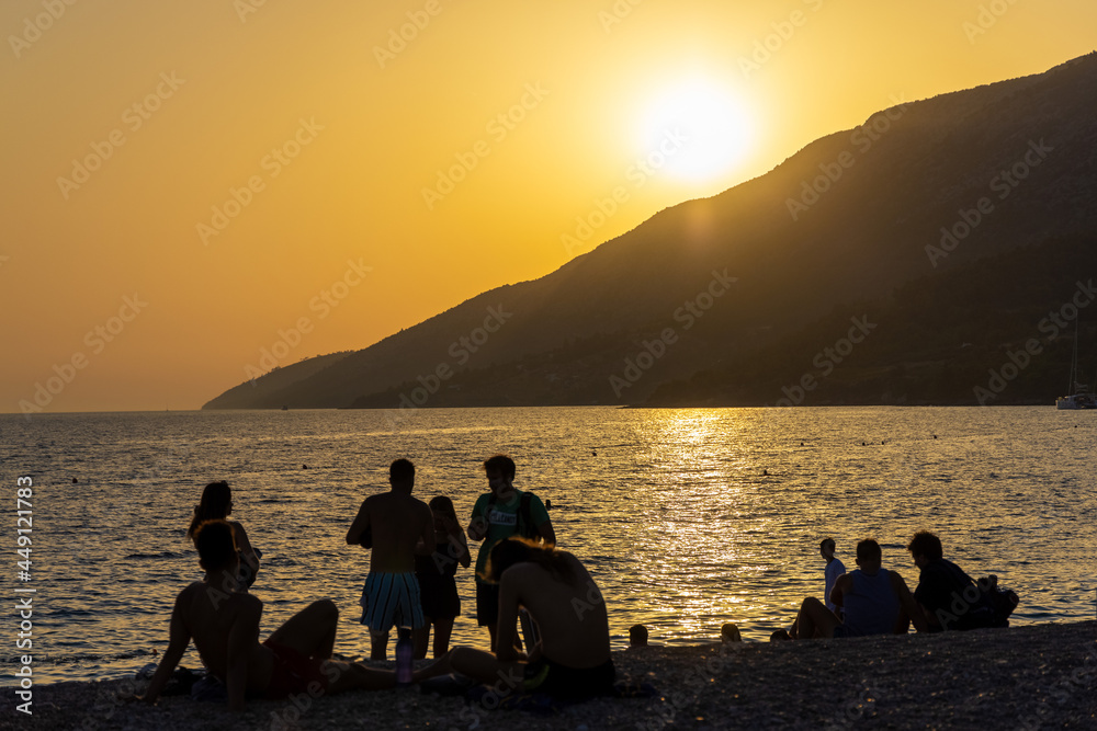 People are watching the sunset on the Zlatni Rat beach near Bol town, Brač Island, the Adriatic Sea, Croatia