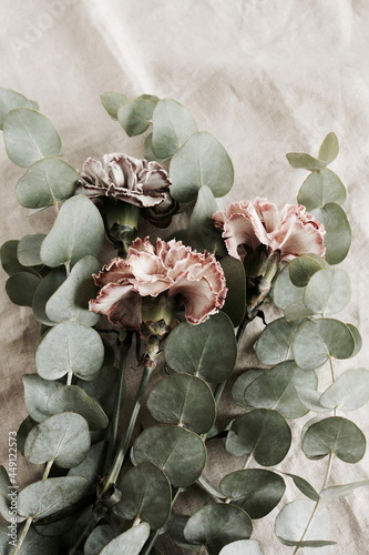 beautiful carnation flowers and eucalyptus leaves bouquet  close up on beige ...