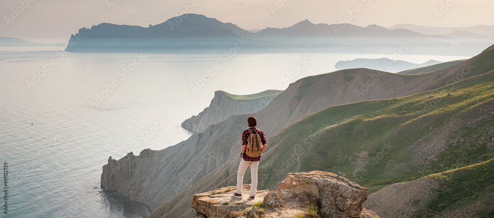 A young Asian woman with a backpack hiking in the summer. Mountain and coastal travel, freedom and an active lifestyle. Breathtaking scenery of the Black Sea coast A young Asian woman with a backpack hiking in the summer. Mountain and coastal travel, freedom and an active lifestyle. Breathtaking scenery of the Black Sea coast