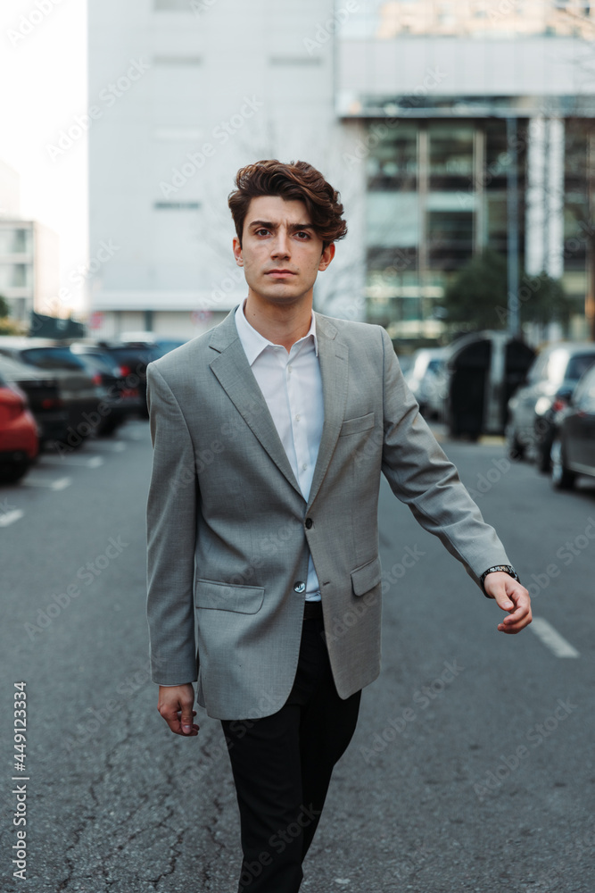 young man in casual suit walking down a street young man in casual suit walking down a street