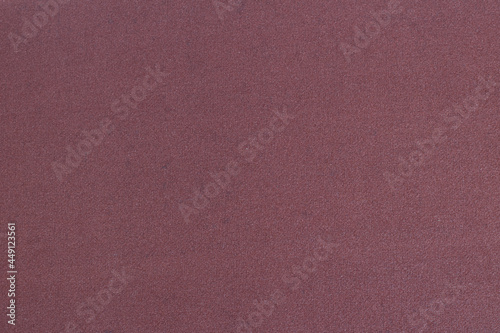 Brown-red sandpaper close-up. Grainy texture.