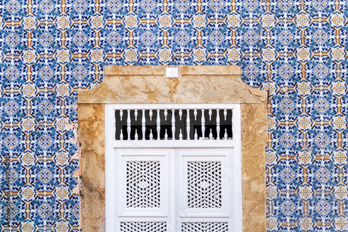 Travel to Portugal. Old vintage facade and door from house exterior in Portuguese typical traditional village or city. Hydraulic ceramic tiles wall