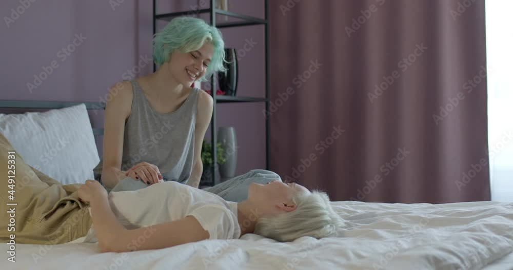 young lesbian couple relaxing on bed, having talk, smoking e-cigarette, side view. Loving ladies enjoy weekends together at home, two women in love. Love, people lifestyle, lgbt, people relationships Stock-Video | Adobe Stock