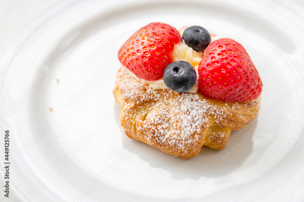 Close up of Danish Pastry Fresh Fruit, Fresh croissant with whipped cream and strawberries blueberries on a white plate Close up of Danish Pastry Fresh Fruit, Fresh croissant with whipped cream and strawberries blueberries on a white plate