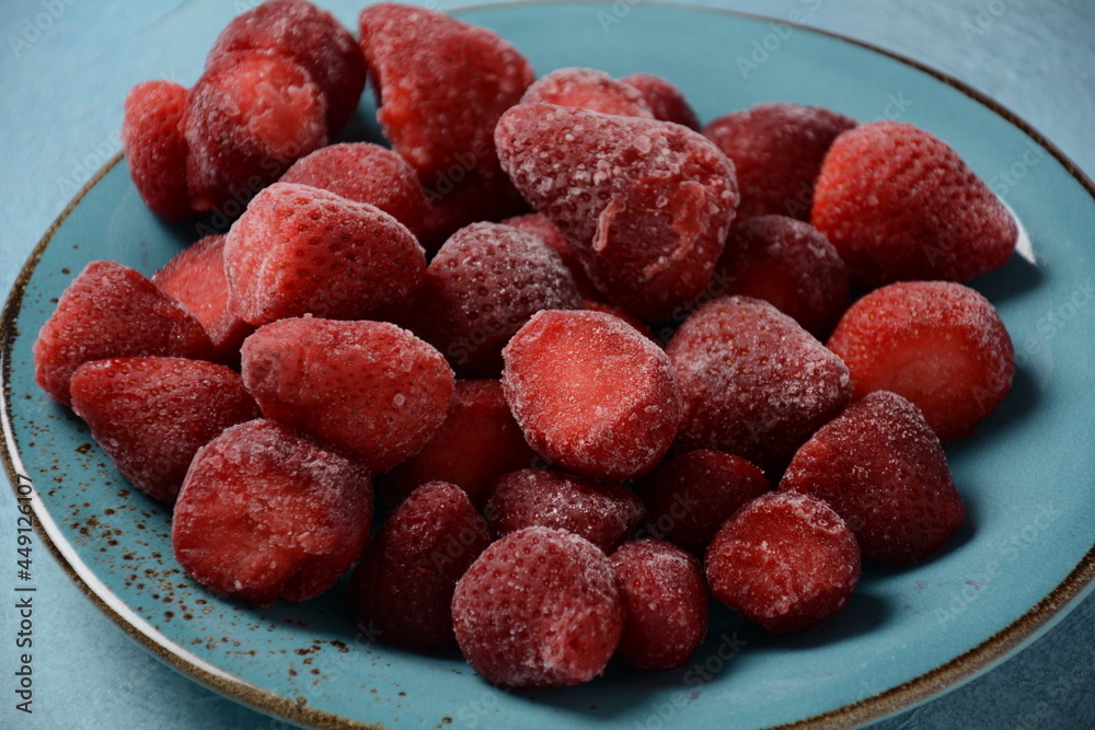 Frozen strawberries in blue plate on blue background Frozen strawberries in blue plate on blue background