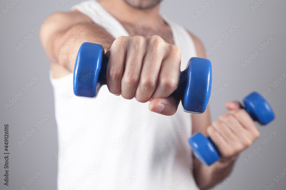Caucasian man holding blue dumbbell.