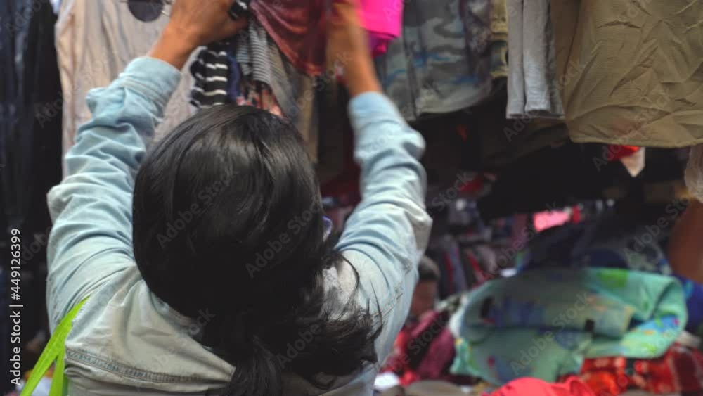 Hispanic woman buying used clothes in market. Latin woman buying clothes in street Hispanic woman buying used clothes in market. Latin woman buying clothes in street
