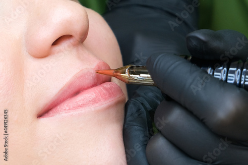 Young woman having permanent makeup on her lips at the beauticians salon.