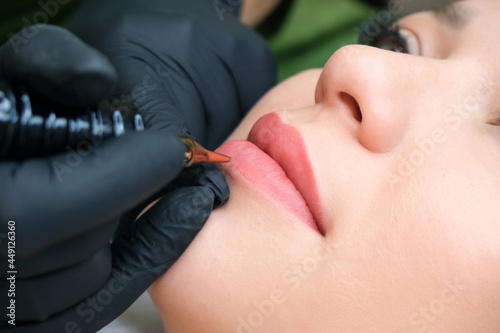 Young woman having permanent makeup on her lips at the beauticians salon. © Elena
