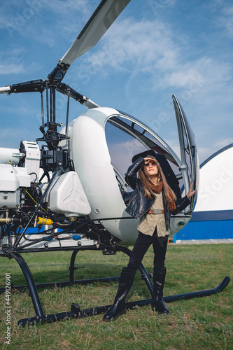 Preteen girl in sunglasses looking at sky near helicopter photo